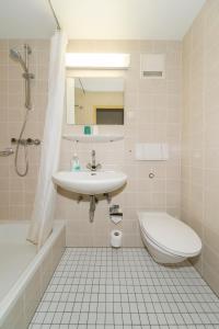 a white bathroom with a sink and a toilet at Hotel Heidler in Niederau