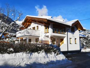 une maison blanche avec de la neige au sol dans l'établissement Haus Marieus, à Umhausen