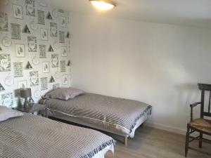 two beds in a room with a wall with pictures at Chambre d'hôtes Logis de Saint Jean in Bayeux