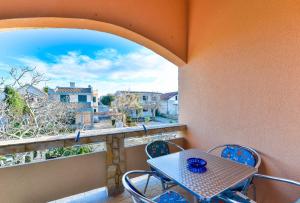 eine Terrasse mit einem Tisch und Stühlen auf dem Balkon in der Unterkunft Apartmani Vugec in Vir