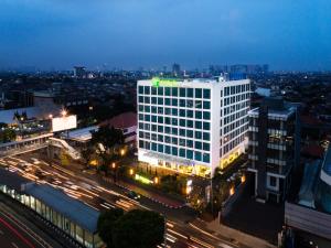 Holiday Inn Express Jakarta Matraman, an IHG Hotel في جاكرتا: مبنى مضاء في مدينة في الليل