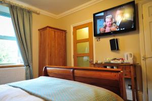 - une chambre avec un lit et une télévision murale dans l'établissement The Wyvill Arms, à Leyburn