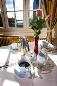 einen Tisch mit einer Tasse Kaffee und einer Vase Rosen in der Unterkunft Hotel Fresena im Dammtorpalais in Hamburg