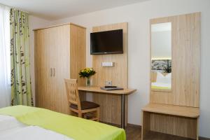 a bedroom with a bed and a desk with a television at Hotel-Gasthof Blaue Traube e.K. in Berching