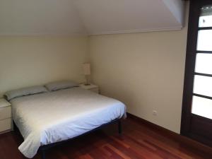 1 dormitorio con cama blanca y ventana en Ático Nuevo con vistas en Cabezón de la Sal