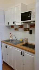 a kitchen with white cabinets and a sink and a microwave at Apartment in the "antique street" in Budapest