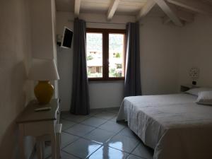 a bedroom with a bed and a window at Hotel Alador in Budoni