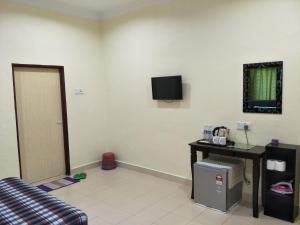 a room with a couch and a television on the wall at Motel Aurora Damai in Pantai Cenang