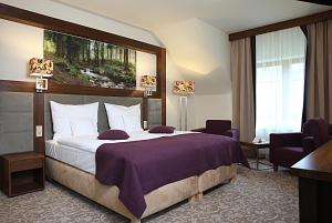 a bedroom with a large bed with a purple blanket at Hotel Mercure Krynica Zdrój Resort&Spa in Krynica Zdrój