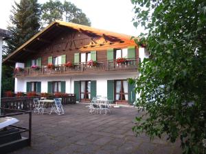 ein Gebäude mit einem Balkon mit Tischen und Stühlen in der Unterkunft Bayersoier Hof in Bayersoien