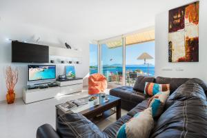 a living room with a couch and a tv at Vistafar - Private Pool & Only 50m to the Sea in Alcudia