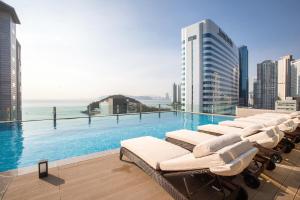 a pool with lounge chairs on the roof of a building at Baymond Hotel in Busan