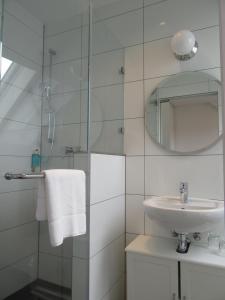 a white bathroom with a sink and a mirror at Minsu Hotel in Mülheim an der Ruhr