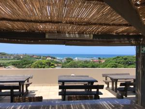 a group of picnic tables under a straw roof at Falling Waters Guest House in Margate