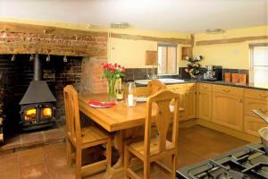 a kitchen with a wooden table and a fireplace at Oak Cottage in Thorndon