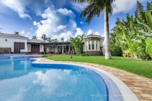 a swimming pool in front of a house with a palm tree at Maspalomas Golf Luxury Villa - Royal Palm in San Bartolomé de Tirajana