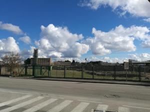 an empty street with a fence and a field at Casa Etimo in Manduria