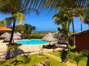 a resort with a swimming pool and palm trees at Hotel Pousada Beleza das Ondas in Cumbuco