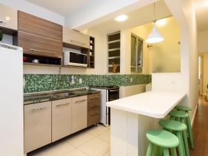 una cocina con encimera blanca y taburetes verdes en Apartamento moderno em Copacabana | SL 363/109 en Río de Janeiro