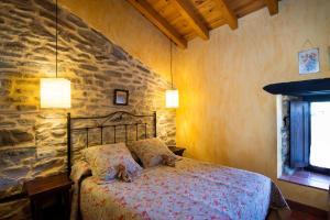 a bedroom with a bed and a stone wall at La Casita de Zalama in San Pelayo - Merindad de Montija