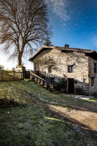 una vieja casa de piedra con un árbol y una valla en La Casita de Zalama, en San Pelayo - Merindad de Montija