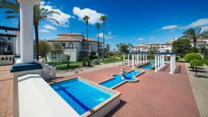 a row of swimming pools with palm trees and houses at Leo San Bruno in Isla Canela