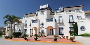 a large white building with potted plants in front of it at Leo San Bruno in Isla Canela