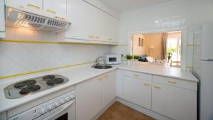 a white kitchen with white cabinets and a sink at Leo San Bruno in Isla Canela