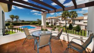 a balcony with a table and chairs and a swimming pool at Leo San Bruno in Isla Canela