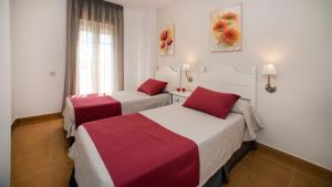 two beds in a hotel room with red and white sheets at Leo San Bruno in Isla Canela