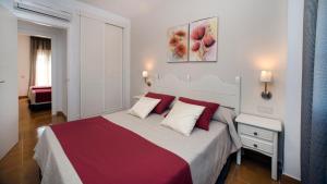 a bedroom with a large bed with red and white pillows at Leo San Bruno in Isla Canela