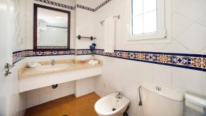 a bathroom with a sink and a toilet and a mirror at Leo San Bruno in Isla Canela