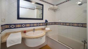 a bathroom with a sink and a tub and a mirror at Leo San Bruno in Isla Canela