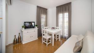 a white living room with a table and a television at Leo San Bruno in Isla Canela