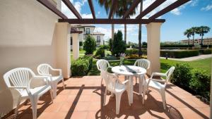 a patio with white chairs and a table on a patio at Leo San Bruno in Isla Canela