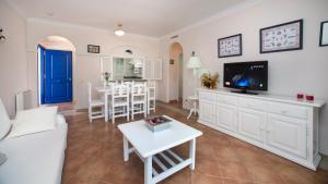 a living room with a white couch and a tv at Leo San Bruno in Isla Canela