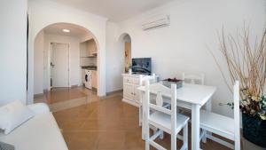 a white kitchen with a white table and chairs at Leo San Bruno in Isla Canela
