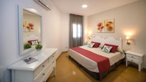 a bedroom with a bed with a dresser and a mirror at Leo San Bruno in Isla Canela +37 photos