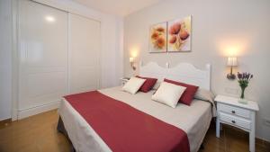 a bedroom with a large bed with red and white pillows at Leo San Bruno in Isla Canela