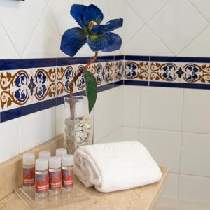 a blue flower in a vase on a shelf in a bathroom at Leo San Bruno in Isla Canela