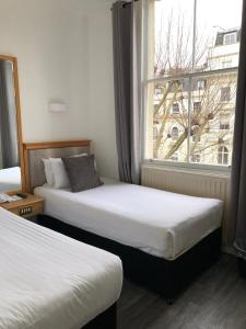 2 camas en una habitación de hotel con ventana en Berjaya Eden Park London Hotel, en Londres