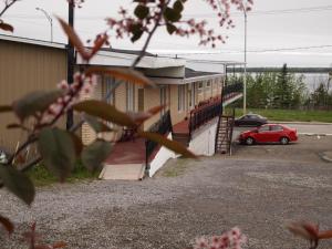 un edificio con un coche rojo estacionado en un estacionamiento en Motel Lyse, en Rimouski