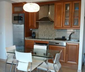 cocina con mesa de cristal y sillas blancas en Apartamento Nules Experience en Mascarell