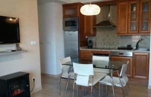 uma cozinha com uma mesa de vidro e cadeiras brancas em Apartamento Nules Experience em Mascarell