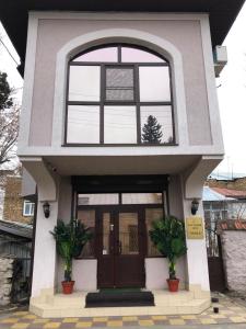 a house with two potted plants in front of a door at Vesta Guest House in Kislovodsk