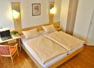 Schlafzimmer mit einem Bett und einem Schreibtisch mit einem Laptop in der Unterkunft Gasthaus Wiemann-Sander in Bad Iburg