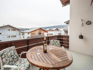 Una botella de vino sentada en una mesa de madera en un balcón en LAAX Homes - Casa Zundra en Flims
