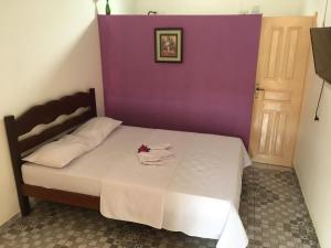 a bed in a room with a purple wall at Algodoal Bela Mar Pousada in Algodoal