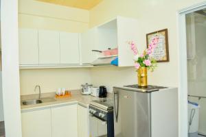 una cocina con armarios blancos y un jarrón de flores en una nevera en MAILZ HAVEN BEAUTIFL 3BR MODERN APRT NEAR SM DOOR-C en Dávao
