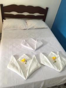 a bed with white towels and yellow flowers on it at Algodoal Bela Mar Pousada in Algodoal
